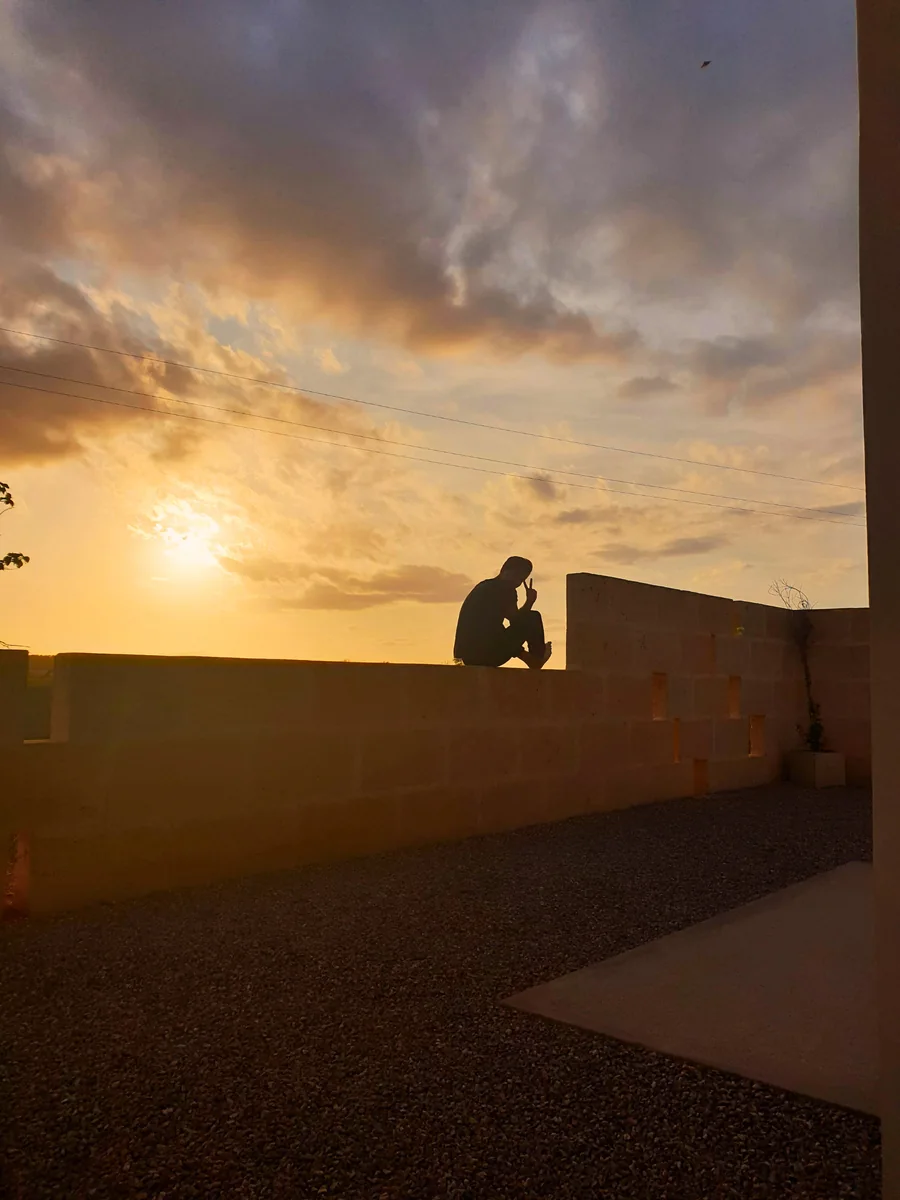 Ein Teilnehmer sitzt abends allein auf der Mauer der Finca